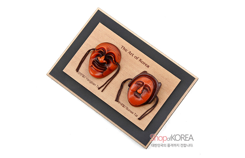 [텍스트: The Art of Korea, 양반탈 / Yangban Tal, 부네탈 / Bunee Tal, Shop of KOREA, 대한민국의 품격까지 전합니다.] 옻칠한 갈색 계열 양반탈·부네탈 입체 장식을 나무 패널 위에 부착한 가로형 목재 액자 구성