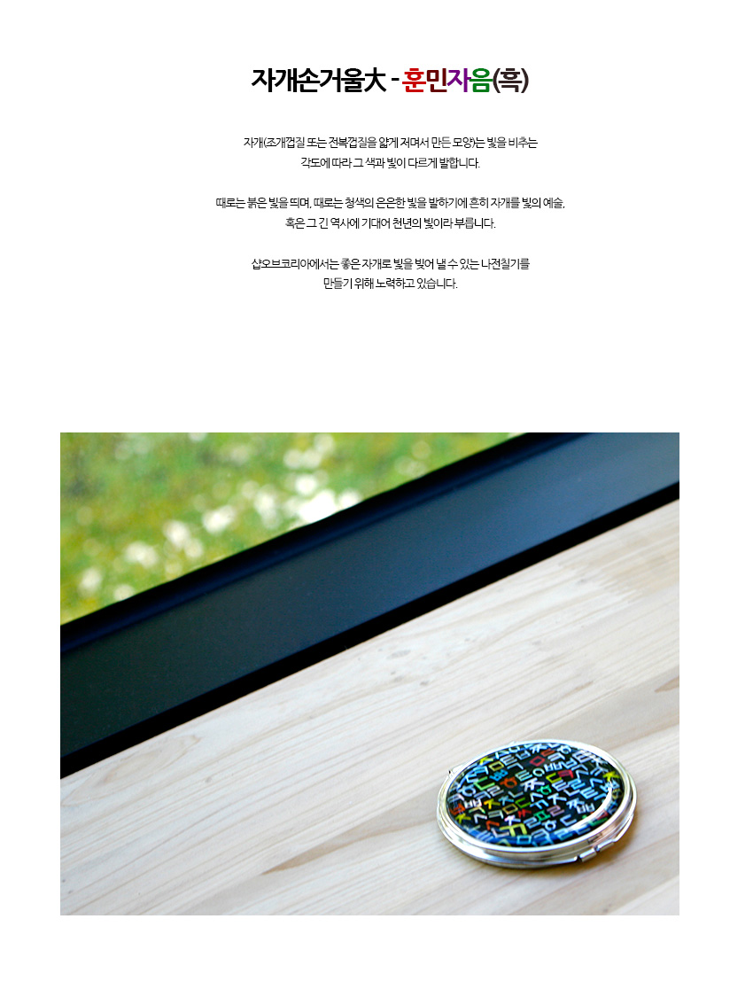 [텍스트: 자개손거울大 - 훈민자음(흑)] 흑색 바탕 위 자개빛이 비치는 다채로운 훈민정음 자모 문양과 금속테 두른 원형 접이식 손거울 이미지