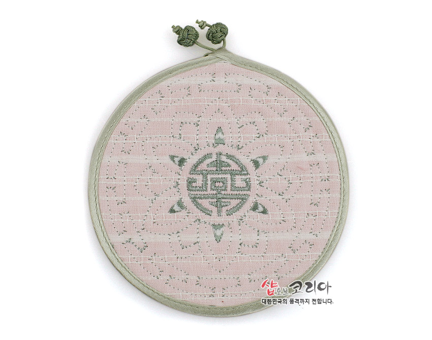 [텍스트: 샵오브코리아 대한민국의 품격까지 전합니다.] 연녹색 수복문 자수와 연꽃 문양이 새겨진 전통 누비 기법 원형 패브릭 컵받침, 끈 매듭 장식 포인트 디자인