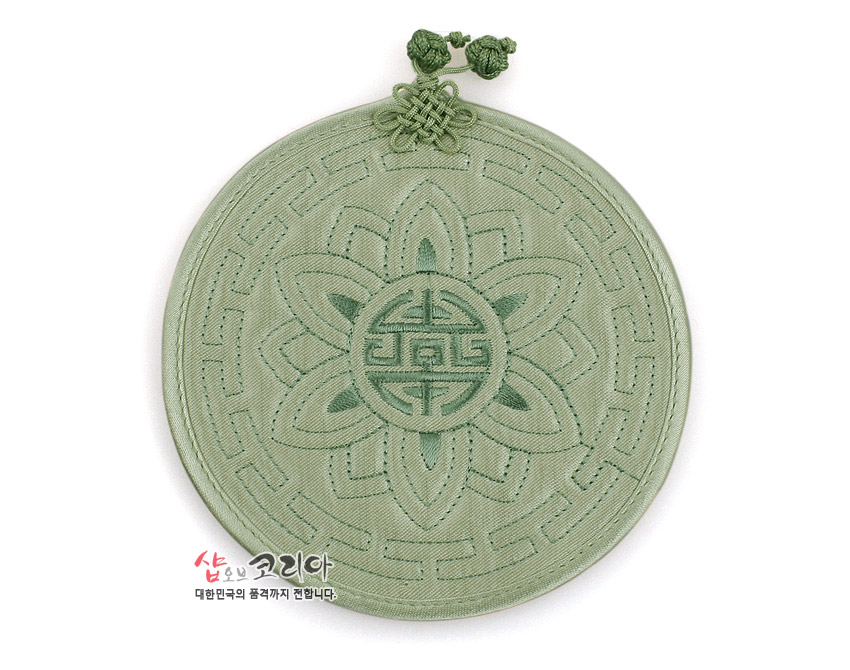[텍스트: 샵오브코리아 대한민국의 품격까지 전합니다.] 연녹색 비단 재질의 원형 누비 컵받침, 중앙 수복문과 연꽃 누비 문양, 상단 전통 매듭 장식 특징