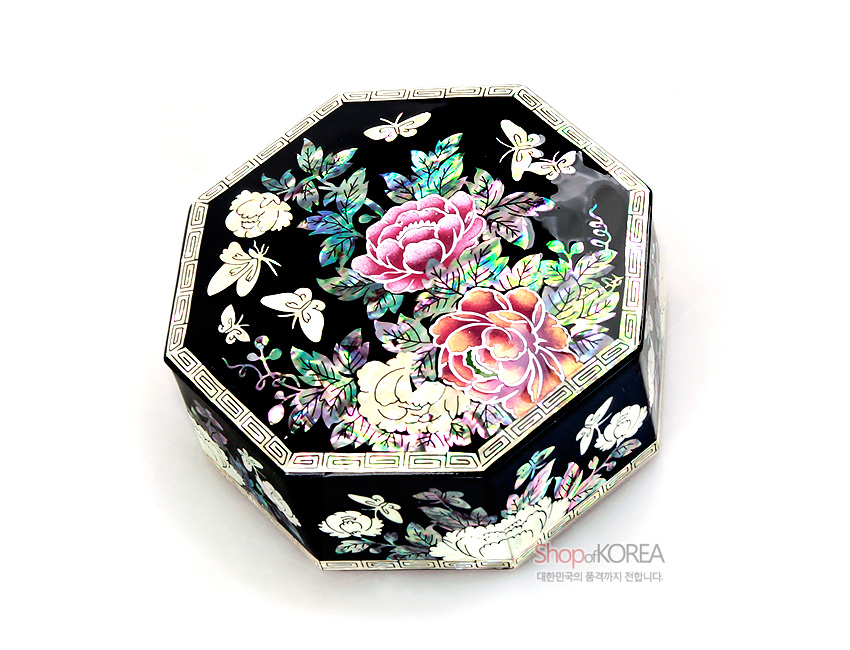 [텍스트: ShopofKOREA 대한민국의 품격까지 전합니다.] 흑색 옻칠 바탕 위 자개 상감 기법으로 목단꽃과 나비 문양을 화려하게 장식한 팔각 나전 보석함 모습