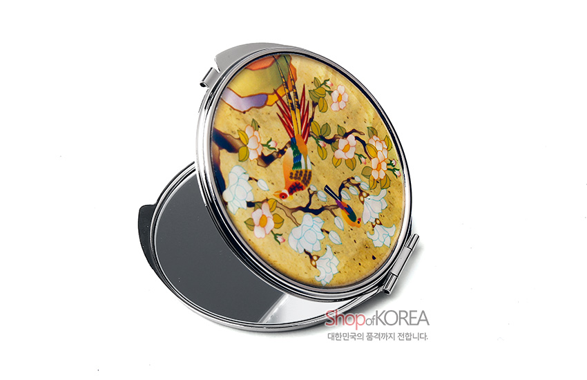 [텍스트: Shop of KOREA, 대한민국의 품격까지 전합니다.] 자개 상감 기법의 원형 금속 손거울, 노란 바탕 위 화조채색과 만개한 꽃문양의 다채로운 색감 돋보이는 디자인