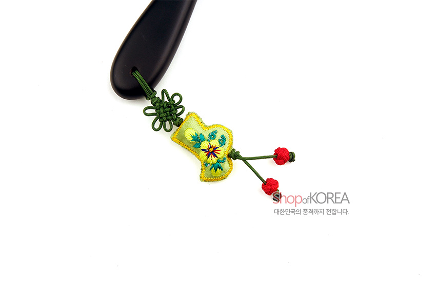 [텍스트: shopofKOREA 대한민국의 품격까지 전합니다.] 검은색 손잡이 끝에 녹색 매듭과 노랑 비단 자수 장식, 붉은 매듭 술이 어우러진 장신구형 손거울 디테일 컷 모습