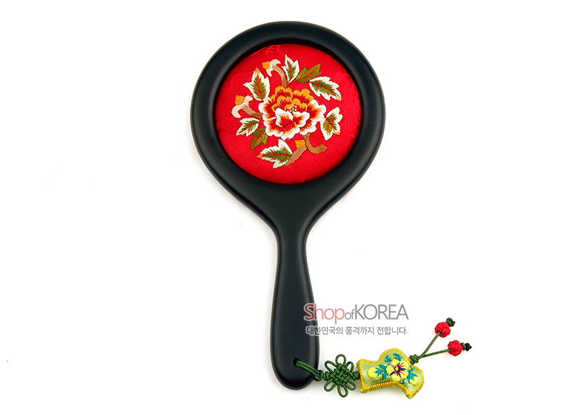 [텍스트: Shop of KOREA 대한민국의 품격까지 전합니다.] 붉은 비단 바탕에 모란 자수를 놓은 원형 장식과 검은 색 금속 손잡이, 노리개 매듭과 노란 비단 수자수 장식 술 구성 이미지