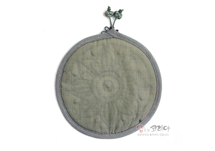 [텍스트: 샵오브코리아 대한민국의 품격까지 전합니다.] 회색 누비 천으로 제작된 원형 컵받침, 가장자리 배색 처리와 상단 전통 매듭 장식 포인트 디자인