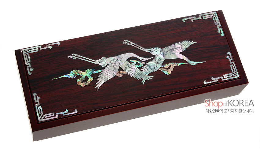 [텍스트: Shop of KOREA 대한민국의 품격까지 전합니다.] 짙은 적갈색 옻칠 나무 바탕 위 자개 상감 쌍학 문양과 모서리 전통 기하학 문양이 장식된 직사각형 자동함 모습