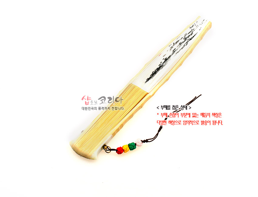 [텍스트: 샵오브코리아 대한민국의 품격까지 전달합니다. <부채를 접은 상태> * 부채 손잡이 부분에 있는 매듭의 색상은 다양한 색상으로 임의적으로 발송이 됩니다.] 대나무 살과 흰 한지에 수묵 난초가 보이는 합죽선, 오색 매듭 술 장식 포인트의 접은 전통 부채 모습