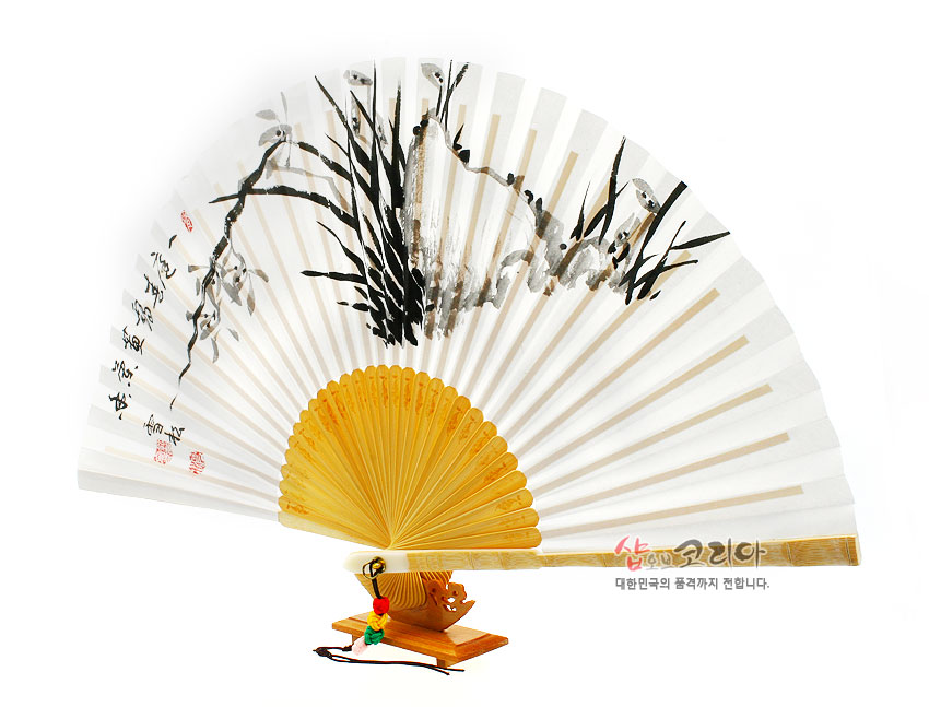 [텍스트: 샵오브코리아 대한민국의 품격까지 전합니다.] 흰 한지 위 수묵 난초와 서예 문양, 대나무 합죽선 살대와 오색 매듭 술 장식 전통 부채 이미지 묘사