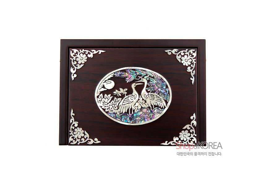 [텍스트: ShopKOREA 대한민국의 품격까지 전합니다.] 짙은 갈색 옻칠 바탕 위 자개 상감으로 송학과 소나무, 달 문양을 넣고 모서리에 백색 초화문을 더한 직사각 명함함 디자인