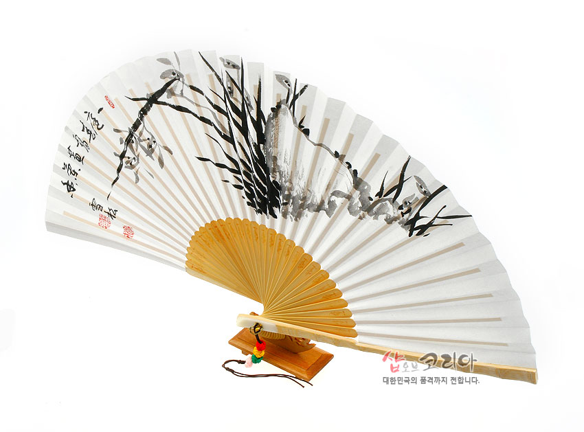 [텍스트: 샵오브코리아 대한민국의 품격까지 전합니다.] 흰 한지 위 수묵 난초와 서예 문양, 대나무 살대와 목제 받침, 배색 술 장식이 조화를 이룬 합죽선 이미지 묘사