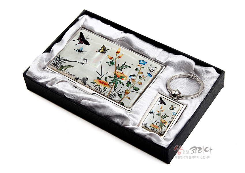 [텍스트: 샵오브코리아 대한민국의 품격까지 전합니다.] 자개 상감 기법의 초충도 꽃과 나비 문양이 은은한 진주광을 띠는 금속 명함집과 키링 세트 구성