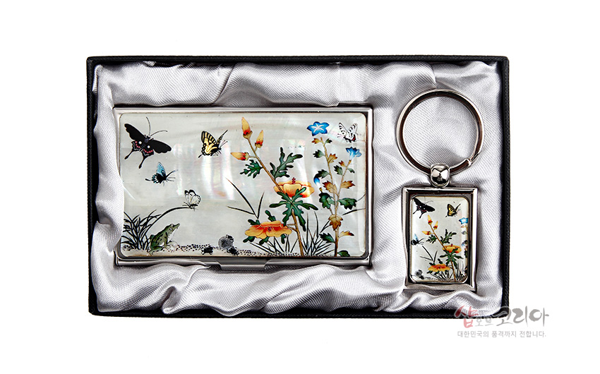 [텍스트: 샵오브코리아 대한민국의 품격까지 전달합니다.] 자개 상감 기법으로 표현한 초충도 꽃과 나비 문양, 은은한 진주색 배경의 금속 명함케이스와 열쇠고리 세트 이미지 설명