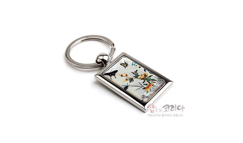 [텍스트: 샵오브코리아 대한민국의 품격까지 전합니다.] 금속 프레임에 초충도 꽃과 나비 문양을 자개 상감으로 넣은 직사각형 키링 디자인