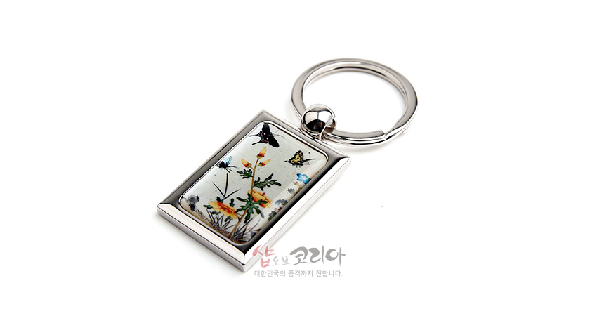 [텍스트: 샵오브코리아 대한민국의 품격까지 전합니다.] 금속 프레임에 자개 상감 기법으로 표현된 초충도 꽃과 나비 문양 직사각 키링 디자인