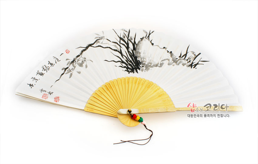 [텍스트: 샵오브코리아 대한민국의 품격까지 전합니다.] 흰 한지 위 수묵 난초와 서예, 붉은 전각 인장 문양, 연한 황색 대나무 살대와 오색 매듭 술 장식의 합죽선 이미지 묘사