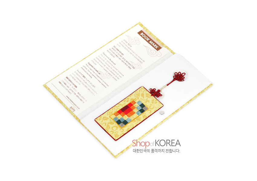 [텍스트: BOOK MARK / Shop of KOREA 대한민국의 품격까지 전합니다.] 황색 비단 바탕에 전통 문양과 다색 조각보 패치워크 장식, 붉은 전통 매듭끈이 어우러진 책갈피 이미지 설명
