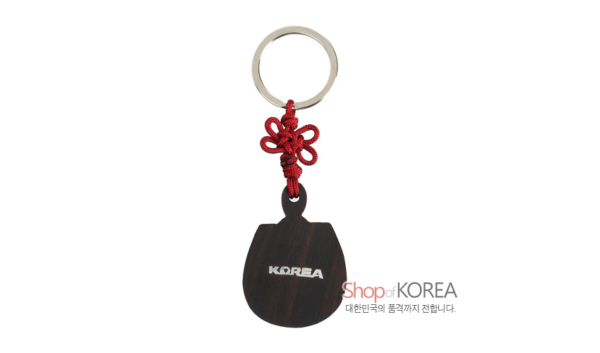 [텍스트: KOREA, Shop of KOREA 대한민국의 품격까지 전합니다.] 흑단 부채 형태 판에 은색 영문 글자 상감하고 붉은 전통 매듭과 금속 링을 더한 열쇠고리 이미지 표현