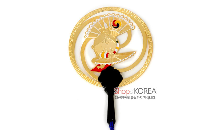 [텍스트: Shop of KOREA 대한민국의 품격까지 전합니다.] 금색 금속 원형틀에 부채춤 인물과 태극 문양을 양각으로 장식하고, 검은색 손잡이와 청색 전통 매듭끈이 더해진 메모홀더 겸용 책갈피 디자인