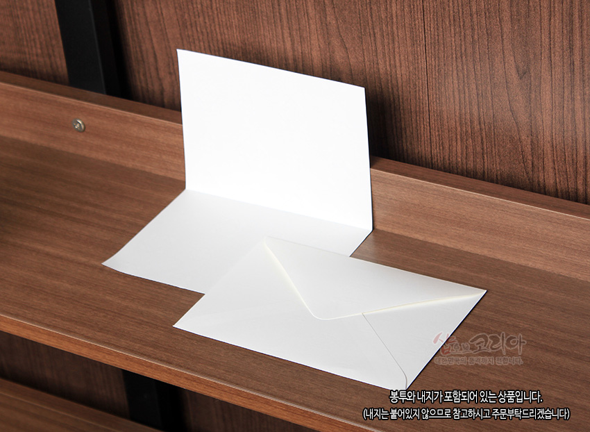[텍스트: 봉투와 내지가 포함되어 있는 상품입니다. (내지는 붙어있지 않으므로 참고하시고 주문부탁드리겠습니다)] 흰색 매끈한 종이 재질의 속지와 삼각 플랩 구조의 흰색 봉투가 나무 무늬 배경 위에 놓인 구성 이미지 설명