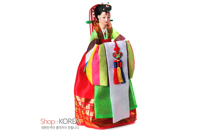 [텍스트: Shop of KOREA 대한민국의 품격까지 전합니다.] 비단 질감 연두·홍색 혼례한복에 금박 전통문양, 오방색 동정과 매듭 노리개, 족두리 장식 신부 인형 모습