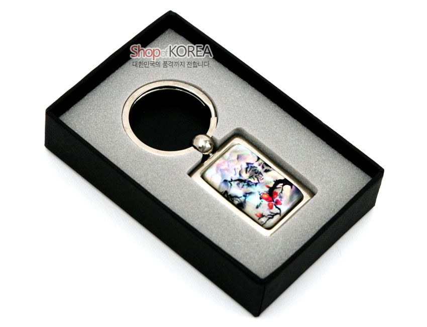 [텍스트: Shop of KOREA 대한민국의 품격까지 전합니다.] 금속 테두리에 채색 자개를 상감한 사각 펜던트, 산수도와 붉은 매화 문양이 어우러진 열쇠고리 구성