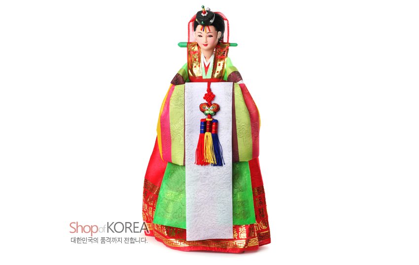 [텍스트: Shop of KOREA 대한민국의 품격까지 전합니다.] 비단 질감 연두·홍색 치마저고리와 금박 전통문양, 오방색 술 매듭 노리개, 흰 장삼과 화려한 족두리로 표현된 전통 신부 인형 모습