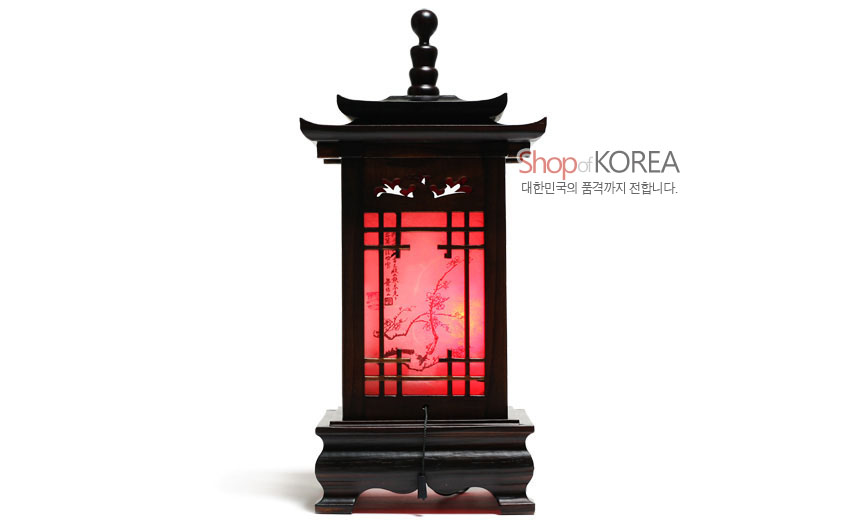 [텍스트: Shop of KOREA 대한민국의 품격까지 전합니다.] 짙은 원목 기와 지붕 구조, 사각 격자 창살과 붉은 조명 속 매화 사군자 문양이 어우러진 전통 좌등 형상