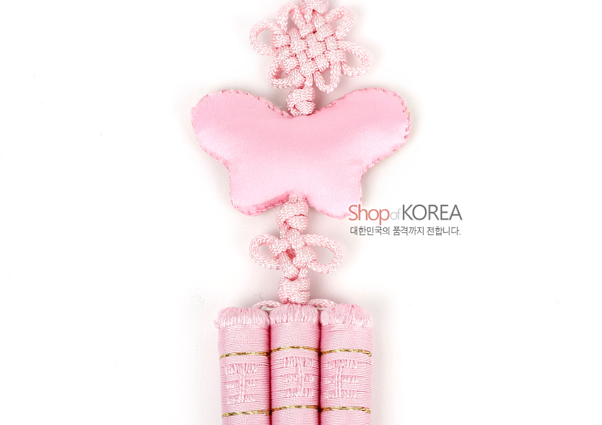 [텍스트: Shop of KOREA 대한민국의 품격까지 전합니다.] 연분홍 비단으로 만든 나비 장식과 전통 매듭, 하단 삼봉 술이 조화를 이루는 자수 노리개 이미지 설명