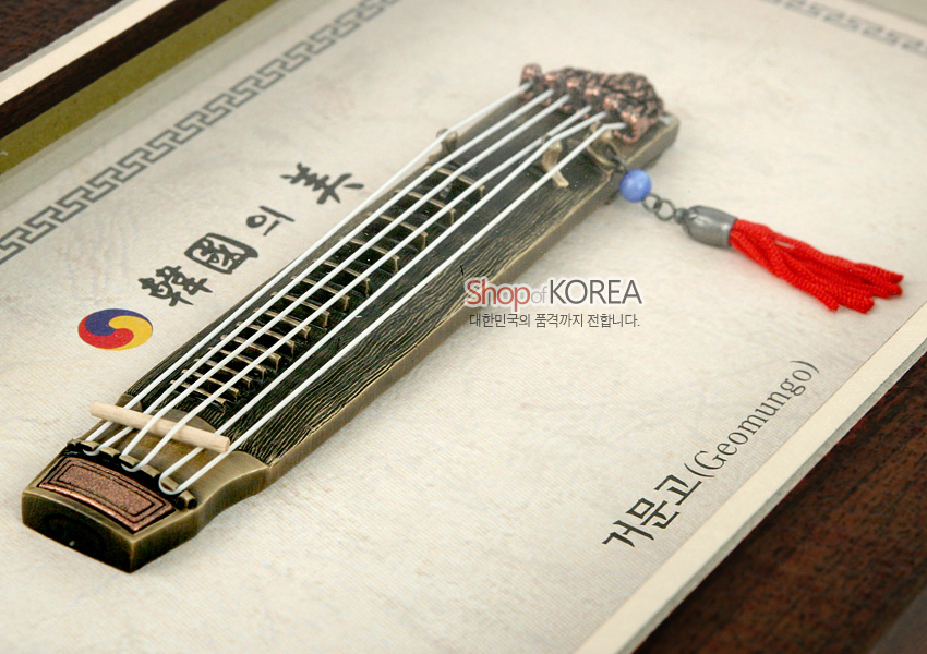 [텍스트: 韓國의美, Shop of KOREA 대한민국의 품격까지 전합니다., 거문고(Geomungo)] 금속 재질 미니어처 거문고와 붉은 술 장식, 태극 문양이 담긴 베이지 색 한지 배경 액자형 장식 이미지