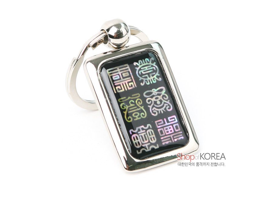 [텍스트: Shop of KOREA, 대한민국의 품격까지 전합니다.] 흑색 바탕 위 다채로운 전서체 한자 문양을 자개 상감 기법으로 장식한 사각 금속 열쇠고리 디자인