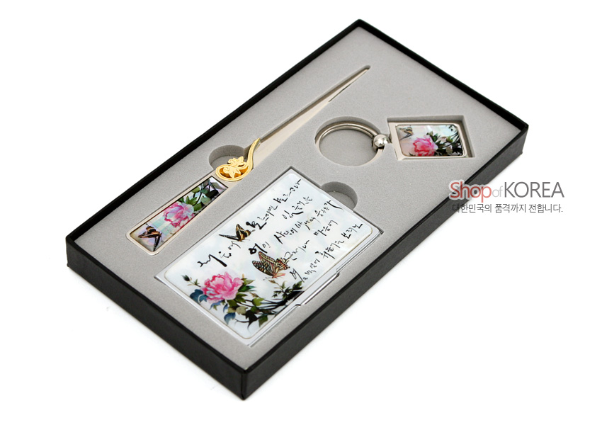 [텍스트: Shop of KOREA / 대한민국의 품격까지 전합니다.] 금속 소재 위 자개 느낌의 광택 처리, 분홍 모란과 나비 문양, 흑색 한글 서예가 어우러진 명함집·편지칼·열쇠고리 세트 이미지