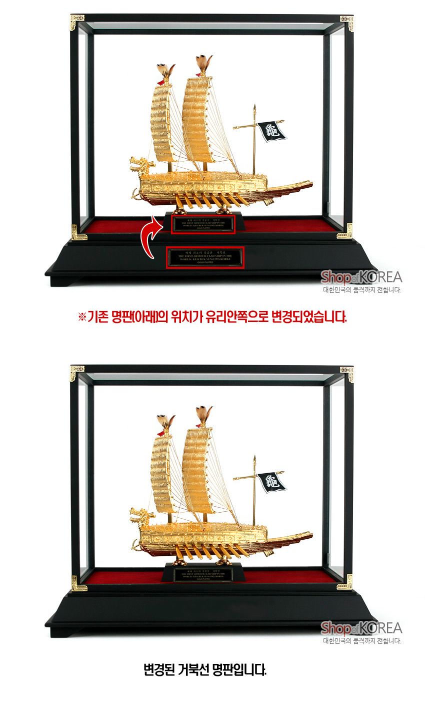 [텍스트: 기존 명판(아래)의 위치가 유리안쪽으로 변경되었습니다. / 변경된 거북선 명판입니다.] 금도금 금속 거북선 모형과 검은 목재 대좌, 적색 펠트 바닥, 투명 케이스 조합의 장식 구성