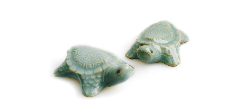 연한 비취색 유약을 입힌 청자 재질 거북 모양 수저받침, 등껍질 육각 기하학 문양과 유려한 곡선 형태가 돋보이는 디자인