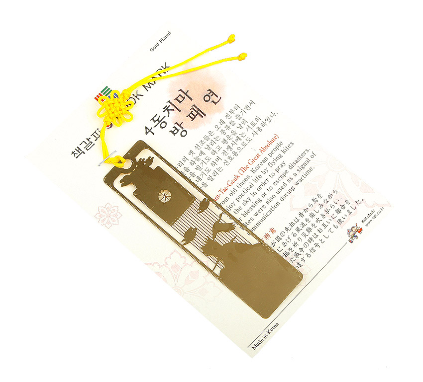 [텍스트: 4동치마 방패연, Made in Korea] 금장 금속 재질 직사각 책갈피에 방패연과 4동치마, 인물과 연줄을 레이저 컷으로 표현하고 노란 전통 매듭 끈을 더한 디자인