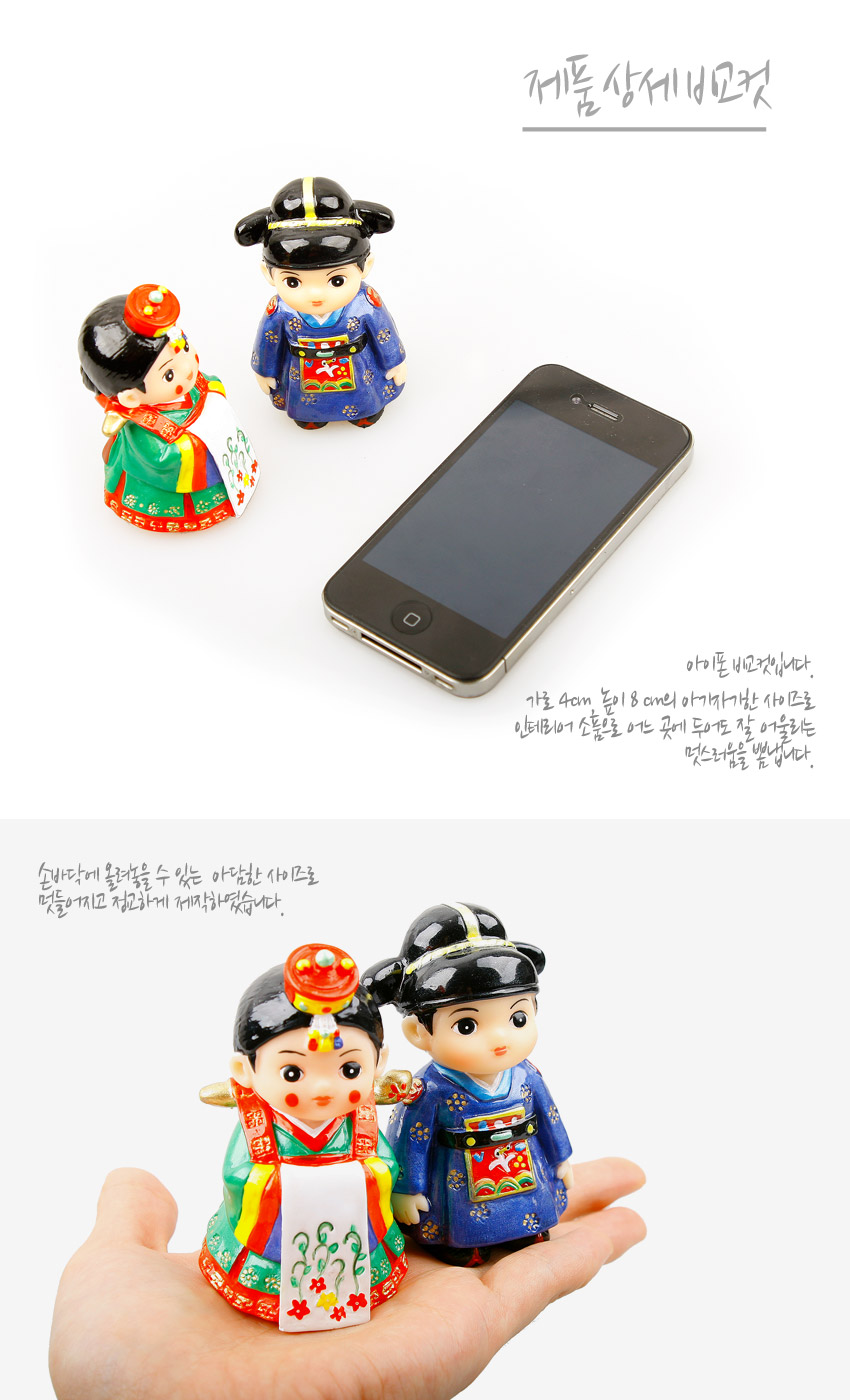 [텍스트: 제품 상세 비교컷 / 아이폰 비교사진입니다. 가로 4cm 높이 8cm의 아기자기한 사이즈로 인테리어 소품으로 어느 곳에 두어도 잘 어울리는 멋스러움을 뽐냅니다. / 손바닥에 올려놓을 수 있는 아담한 사이즈로 만들어지고 정교하게 제작되었습니다.] 청색과 녹색, 적색 한복에 금색 문양을 그려 넣은 플라스틱 왕과 왕비 민속 인형 세트 장식
