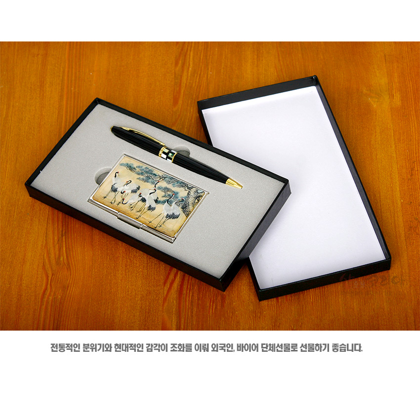 [텍스트: 전통적인 분위기와 현대적인 감각이 조화를 이뤄 외국인, 바이어 단체선물로 선물하기 좋습니다.] 금속 재질 명함케이스에 군학도 회화풍 학 문양과 청·황토색 계열 색채 장식, 금장 포인트의 흑색 볼펜이 포함된 세트 구성
