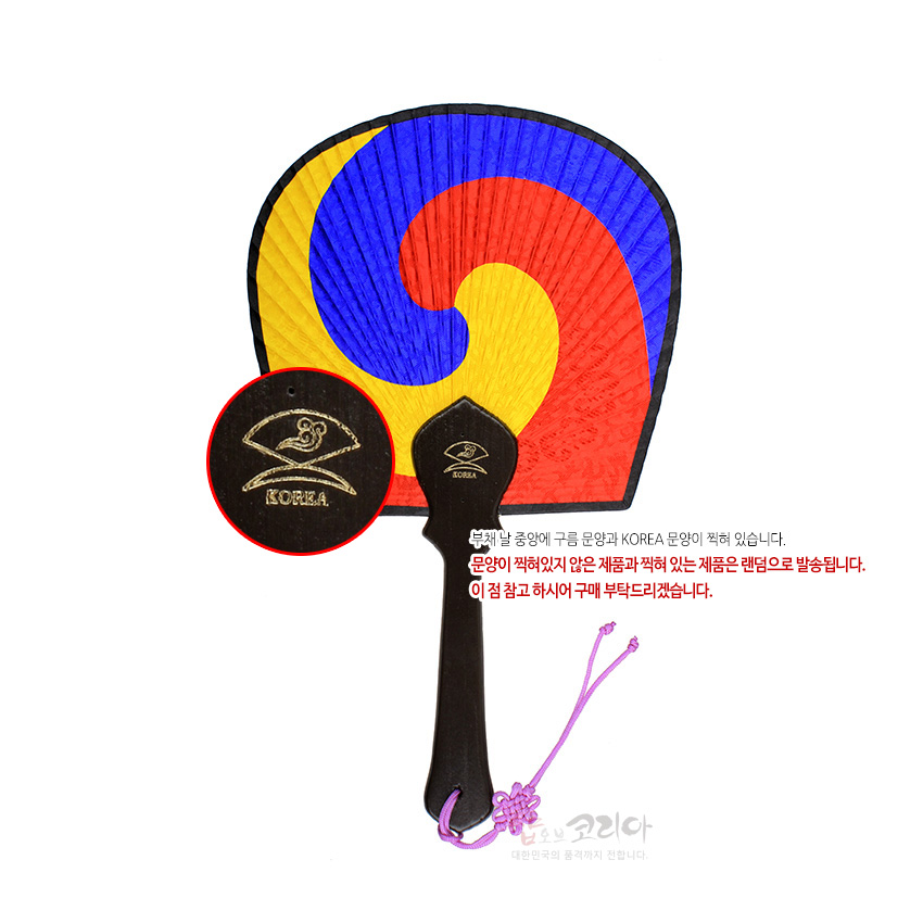 [텍스트: KOREA / 문양이 찍혀있지 않은 제품과 찍혀 있는 제품은 랜덤으로 발송됩니다. 이 점 참고 하시어 구매 부탁드리겠습니다.] 청·홍·황 삼색 태극 문양 종이 부채살과 짙은 갈색 나무 손잡이, 보라색 전통 매듭 끈 장식의 부채 이미지 설명