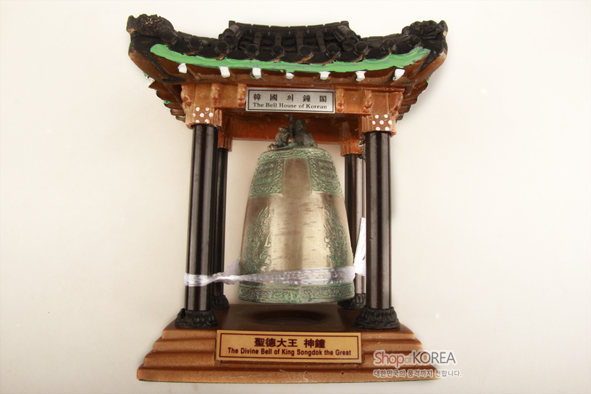 [텍스트: 韓國의 鐘閣 / The Bell House of Korean / 聖德大王 神鐘 / The Divine Bell of King Songdok the Great] 청동 질감의 에밀레종 모형과 녹색 기와, 흑갈색 목조 기둥이 조화된 전통 종각 형식 장식품 표현