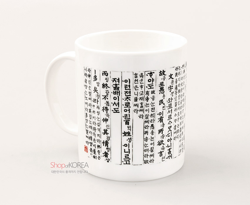 [텍스트: 하늘과 땅 사이에 사람이 있어...] 백색 도자 머그컵에 흑색 훈민정음 언해 세로 필서와 붉은 낙관이 인쇄된 전통 한글 디자인 머그컵 표현