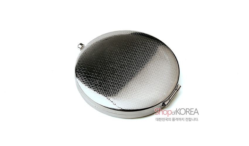 [텍스트: ShopdKOREA 대한민국의 품격까지 전합니다.] 은은한 광택의 실버 톤 금속으로 제작된 원형 원터치 손거울, 미세한 격자 무늬 양각 표면 디자인