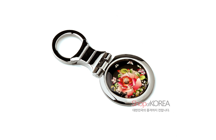 [텍스트: Shop of KOREA 대한민국의 품격까지 전합니다.] 흑색 바탕 위 자개 상감 기법으로 장미와 나비 문양을 표현한 금속 원형 손거울 디자인