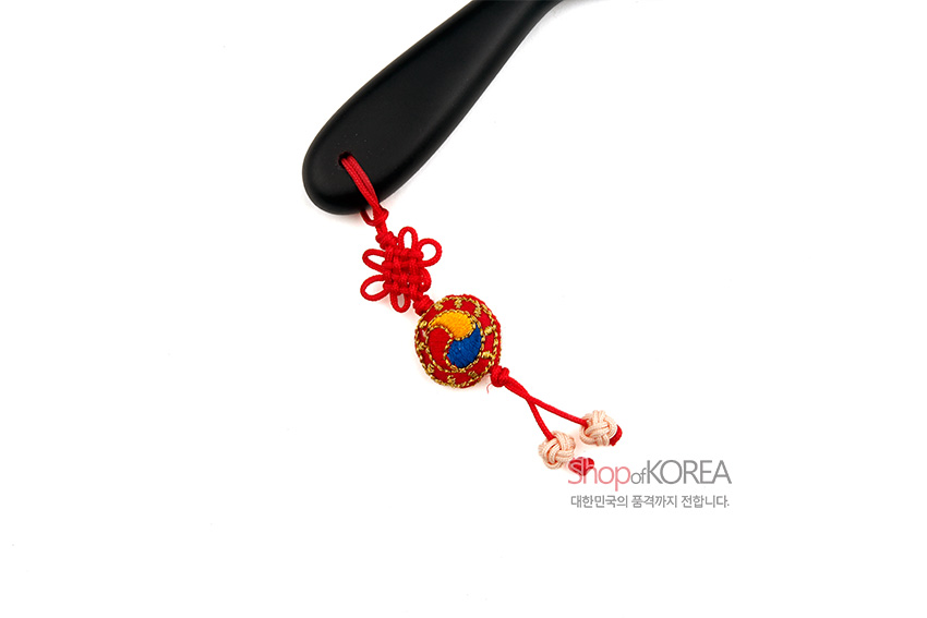 [텍스트: Shop of KOREA 대한민국의 품격까지 전합니다.] 흑색 손잡이에 붉은 전통 매듭과 태극 문양 자수 장식, 복주머니 매듭술 포인트 디자인