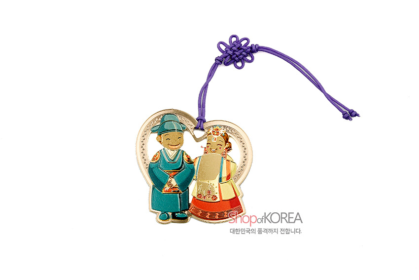 [텍스트: Shop of KOREA 대한민국의 품격까지 전합니다.] 금속 하트형 테두리에 채색된 전통 혼례복 신랑신부 문양과 보라색 매듭 장식 끈이 어우러진 책갈피 디자인