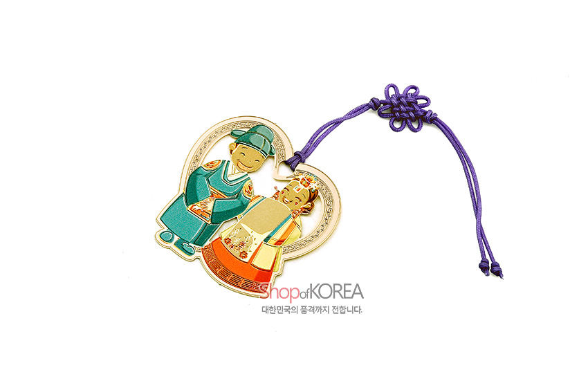[텍스트: Shop of KOREA 대한민국의 품격까지 전달합니다.] 금속 재질 하트형 틀에 전통 혼례복 신랑·신부 채색 문양, 보라색 한국 매듭 끈 장식 책갈피 이미지 설명