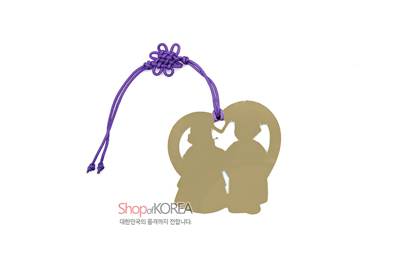 [텍스트: Shop of KOREA 대한민국의 품격까지 전합니다.] 금속 재질 하트형 틀 안 전통 혼례복 인물 실루엣 문양과 보라색 한국 전통 매듭 끈이 조화를 이룬 책갈피 디자인