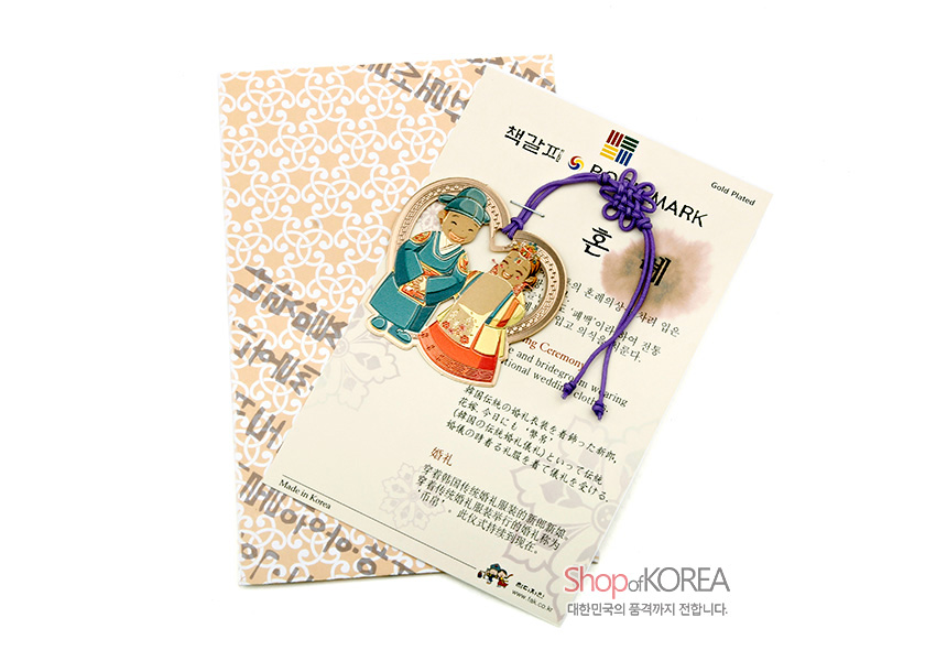 [텍스트: 책갈피 BOOKMARK 혼례 Made in Korea Shop of KOREA 대한민국의 품격까지 전합니다.] 금속 재질 하트형 테두리 안에 전통 혼례복 신랑·신부 문양과 보라색 전통 매듭 끈 장식 특징 책갈피 이미지 설명