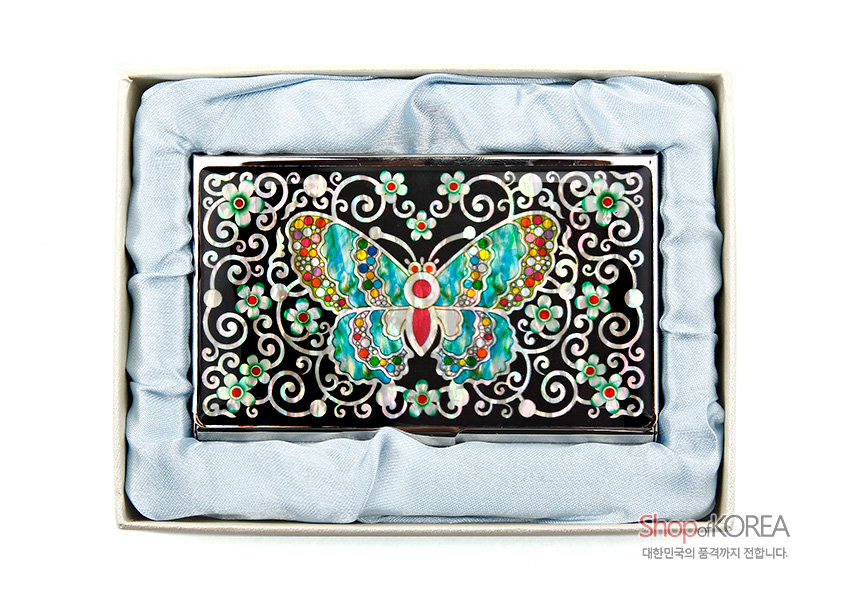 [텍스트: Shop of KOREA 대한민국의 품격까지 전합니다.] 흑색 금속 바탕 위에 자개 상감 기법으로 표현된 다채로운 채색 나비와 꽃넝쿨 문양이 조화를 이룬 명함집 모습