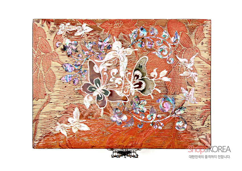[텍스트: ShopofKOREA 대한민국의 품격까지 전합니다.] 적색 비단 직물 바탕 위 자개 상감으로 표현된 나비와 꽃, 덩굴무늬가 화려하게 펼쳐진 직사각 보석함 상판 장식 모습