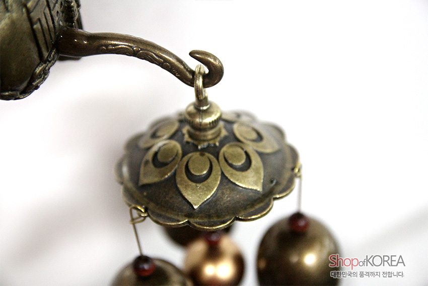 [텍스트: Shop of KOREA 대한민국의 품격까지 전합니다.] 앤틱한 청동빛 금속 재질, 꽃잎 형태 양각 문양이 둘린 상부 장식과 둥근 방울이 매달린 전통 풍경 종 장식