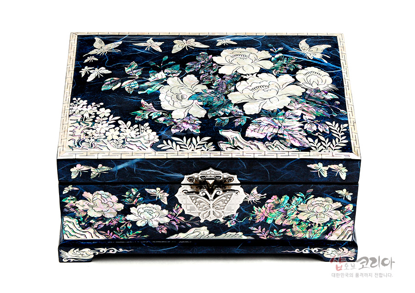 [텍스트: 샵오브코리아 대한민국의 품격까지 전달합니다.] 짙은 청색 옻칠 바탕 위에 자개 상감으로 목단과 나비, 만개한 꽃무늬를 정교하게 장식한 직사각형 보석함 디자인